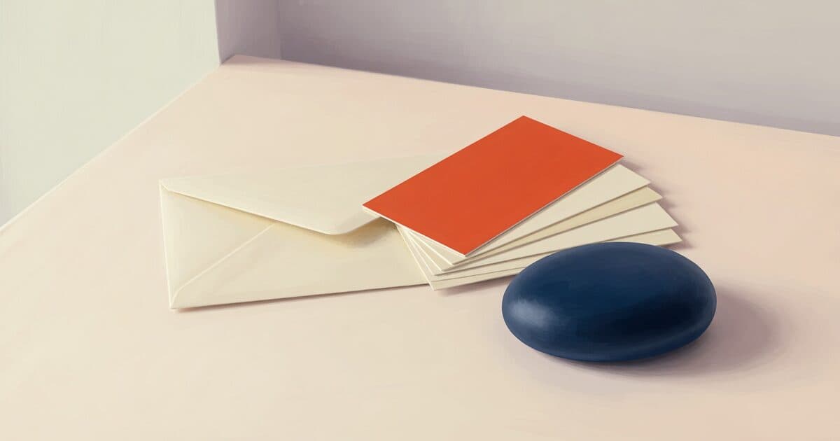 A blank cream envelope, a fan of slips with a vermilion one on top, and a navy paperweight.
